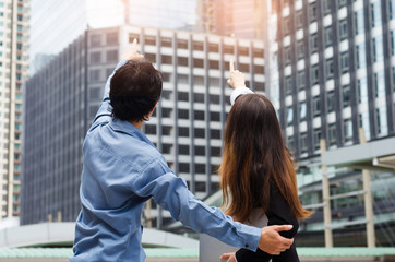 business man and business woman looking foreward at outdoor and point to modern building business city center.