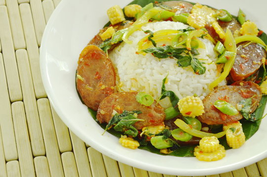 spicy stir fried Chinese pork sausage with basil leaf and rice on plate