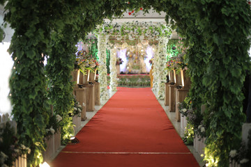 Decorations leaves and flowers with tent on the way to the wedding stage. Indoors wedding ceremony decorations.