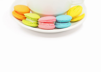 Obraz na płótnie Canvas Colorful macaron cookies with tea cup on white background, copy space.