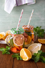 Fresh fruit lemonade with straw in mugs with napkin and mint on wooden background