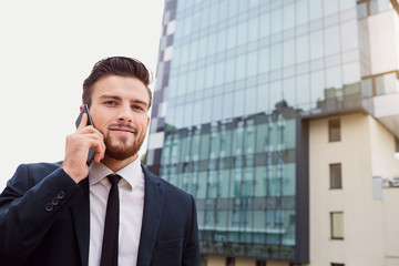 Businessman speaks on the phone outdoors. Business people.