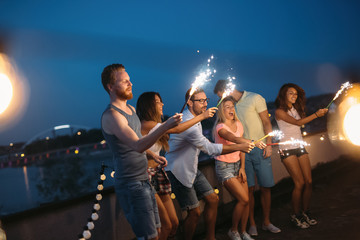 Happy friends lighting sparklers and enjoying freedom