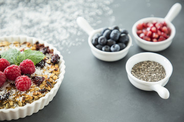 Healthy snack - a vegan tart with raspberries and blurry cup containers with fruit and chia seeds