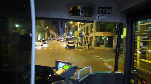 BARCELONA - MAY 11, 2018: Interior of moving bus along city streets at night. The city attracts 10 million tourists annually
