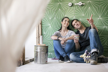 Couple renovating new house, sitting on ground planning bathroom