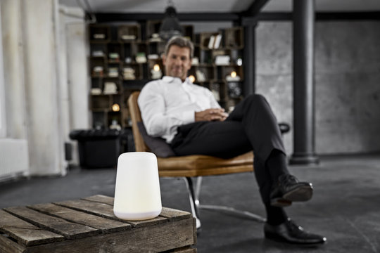 Mature man using voice-controlled digital assistant in loft