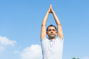 Indian man doing yoga and pressing hands together above head