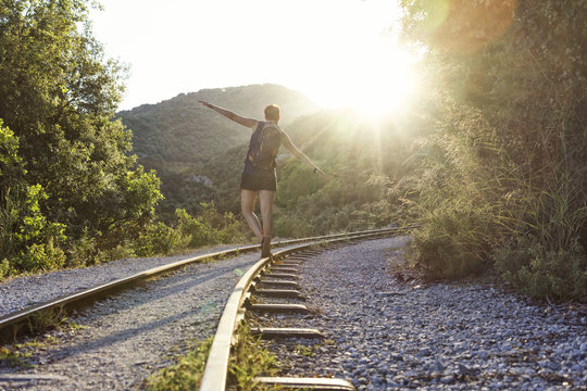 Greece, Pilion, Milies, back view of woman balancing along rails of Narrow Gauge Railway at sunset
