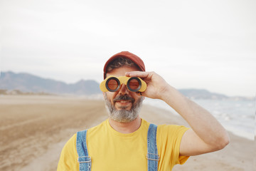 Bearded man using binoculars on the beach