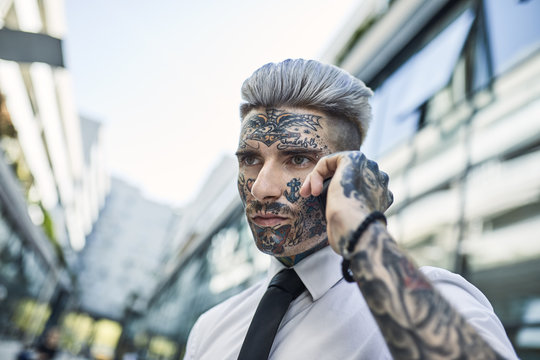 Young businessman with tattooed face, talking on he phone