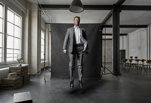 Mature businessman floating in front of black backdrop in loft