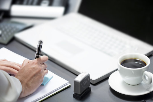 Making notes while working on laptop