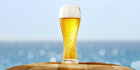 summer beer on desk and blurred sea landscape 
