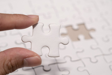 hand with last piece of Jigsaw puzzles with blank copyspace