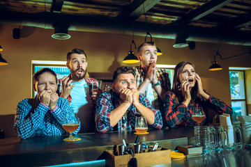 Sport, people, leisure, friendship and entertainment concept - happy football fans or male friends drinking beer and celebrating victory at bar or pub