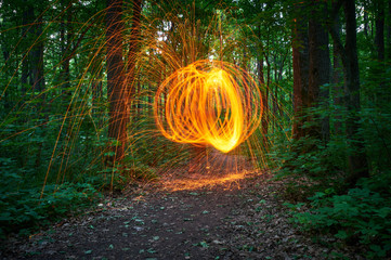 Burning steel wool spinned in the forest. Showers of glowing sparks from spinning steel wool