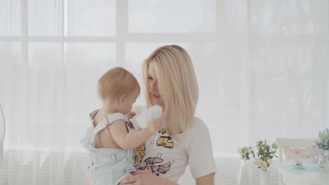 Mother playing with her beautiful daughter in the room. Happy family. Slow motion