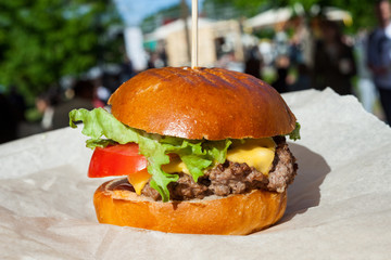 Fresh burger cooked at barbecue outdoors in craft paper. Street fast food.