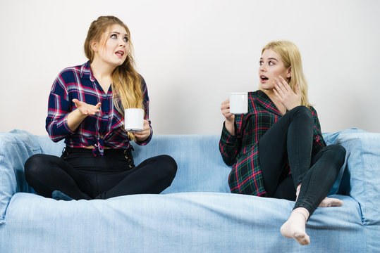 Female friends sitting on sofa talking