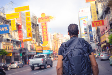 Fototapeta premium men backpacker looking at the famous place of Yaowarat road in Chinatown Bangkok during day, Thailand , Southeast asia .