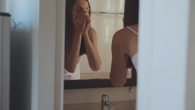Young woman is washing herself face at home in the morning