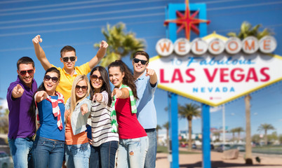 travel, tourism and people concept - group of happy friends pointing at you over welcome to fabulous las vegas sign background