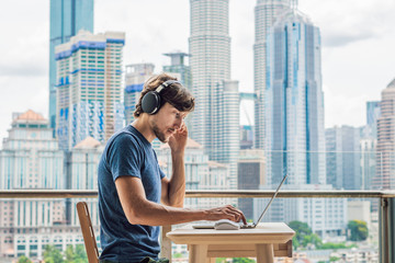 Young man teaches a foreign language or learns a foreign language on the Internet on her balcony...