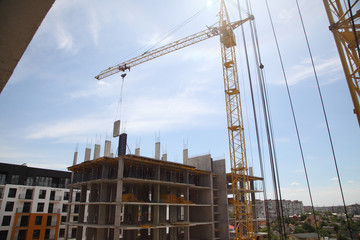 A modern new building. Working crane on the construction of the house. Construction site with cranes on sky background. 