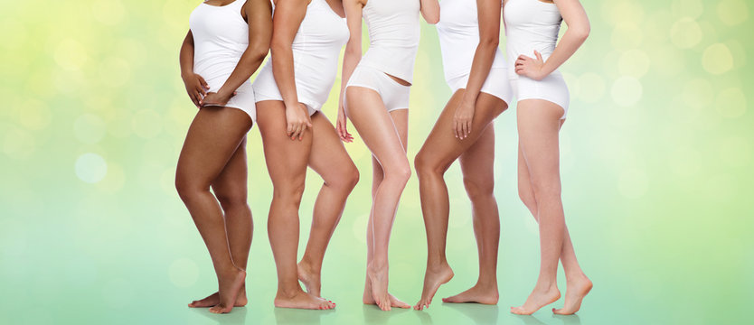 beauty, body positive and people concept - group of diverse women in white underwear over summer green lights background