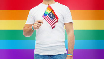 lgbt, same-sex relationships and homosexual concept - close up of man wearing gay pride rainbow awareness wristbands and holding american flag