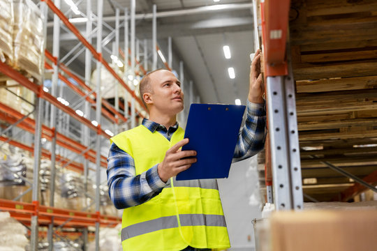 logistic business, shipment and people concept - male worker or supervisor with clipboard in reflective safety vest at warehouse