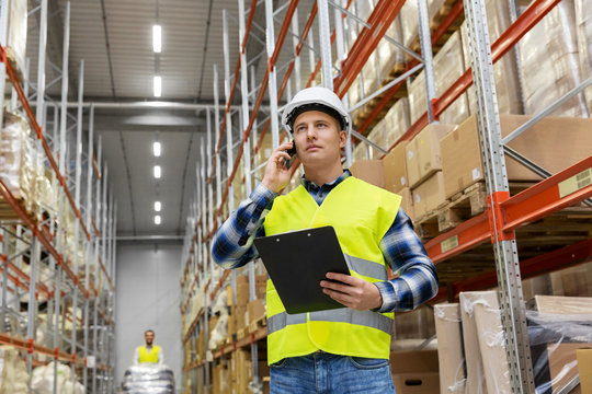 logistic business, technology and shipment concept - businessman calling on smartphone at warehouse