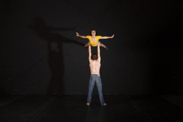 Jóvenes realizando ejercicios de portes acrobáticos en estudio de fotografía