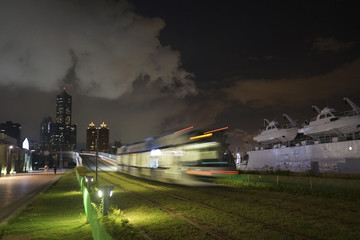 The view of LRT (light rail transit) in Kaohsiung City, Taiwan. When it passes at night. You can also see 85 Sky Tower far away in this photo.