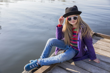 Pretty young girl relaxing near the river in trip in sunny day. Fashion and attractive model