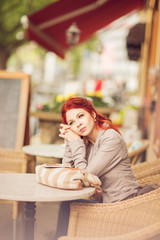 young beautiful woman in a street cafe waiting for a coffee, summerly urban mood