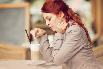 young beautiful woman in a street cafe enjoying a coffee, summerly urban mood