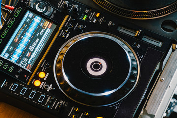 Fototapeta premium Sprzęt DJ-ski z kontrolą ścieżki muzycznej i mikserem na nocnej imprezie klubowej