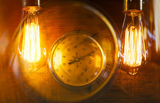 Vintage glowing light bulb lamp hanging next to an old speedometer. Interior decoration in old style luxury design.
