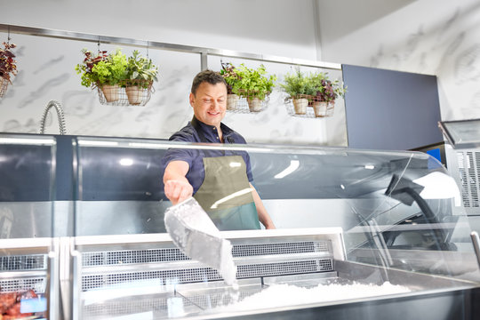 Food Sale, Small Business And People Concept - Male Seller With Scoop Adding Ice To Fridge At Grocery Store