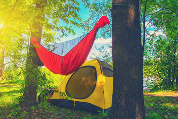 yellow tent and a red hammock in the camping in the summer park. Travel and adventure concept