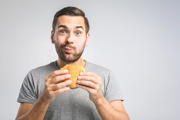 Young man holding a piece of hamburger. Student eats fast food. Burger is not helpful food. Very...