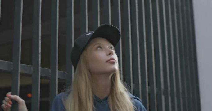 Trendy girl wearing cap and blue sweatshirt haves fun . City urban style. 4K video shooting by handheld gimbal
