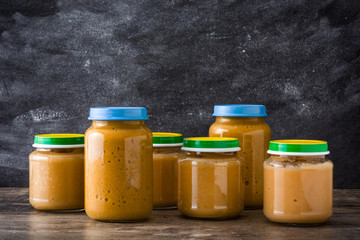 Baby food: Jar with fruit puree on wooden table