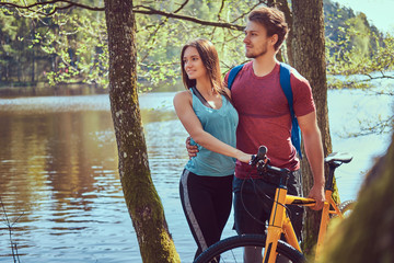 Obraz premium Group of young friends hiking through the forest with bikes on a beautiful summer day