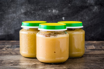 Baby food: Jar with fruit puree on wooden table