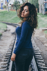 Young sexy girl with long hair in jeans on a railway. Alluring woman looking at camera