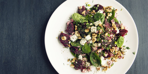 Beetroot salad with cottage cheese, baby spinach and walnuts. European cuisine. Organic food. Vegetarian appetizer. Healthy lifestyle. Simple side dish. Copy space. Top view. Wide photo.