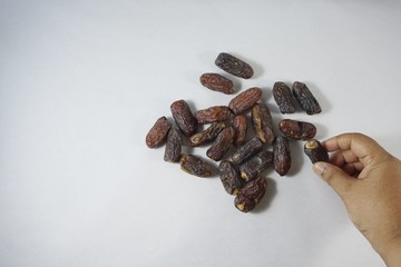 A hand holding a dried dates isolated on white background